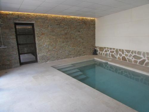 einen Pool in einem Zimmer mit Ziegelwand in der Unterkunft Casa Rural El Parque in Navalcán