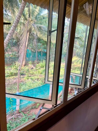 a window with a view of a palm tree at Wood House Near Isha And Karunya University by Shivalaya in Alāndurai
