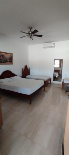a room with two beds and a ceiling fan at Pousada e Pub Chalé do Rock in São João Batista do Glória