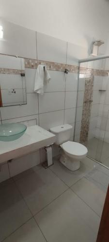 a white bathroom with a toilet and a sink at Pousada e Pub Chalé do Rock in São João Batista do Glória