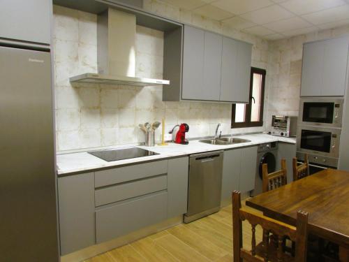 eine Küche mit weißen Schränken und einem Waschbecken und einem Tisch in der Unterkunft Casa Rural El Parque in Navalcán