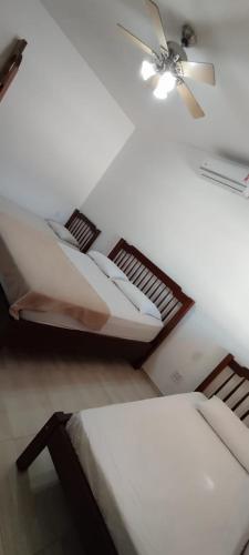 a room with two beds and a ceiling fan at Pousada e Pub Chalé do Rock in São João Batista do Glória