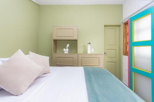 a bedroom with a white bed and a green door at Hotel Chromatic in Guatapé