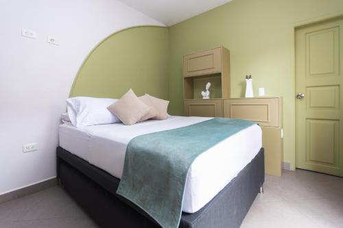 a bedroom with a large white bed with a green wall at Hotel Chromatic in Guatapé