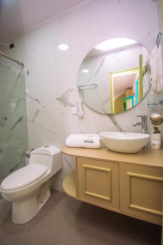 a bathroom with a toilet and a sink and a mirror at Hotel Chromatic in Guatapé