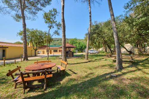 a picnic table and benches in a park with trees at Camping Esponellà in Esponellá
