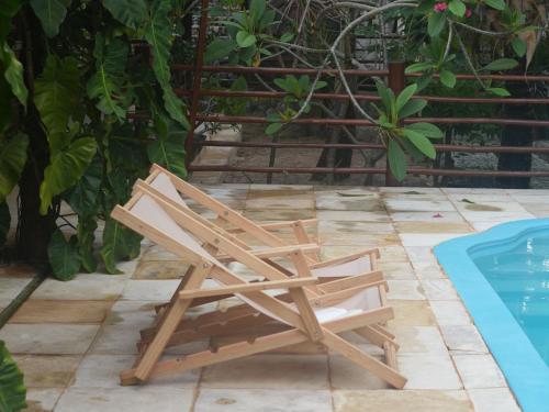 a wooden chair sitting next to a swimming pool at Casa de hóspedes Balibar Cumbuco in Cumbuco