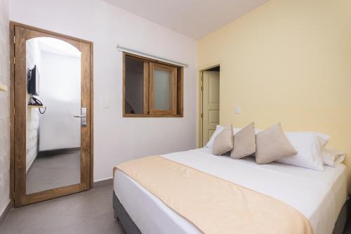 a bedroom with a large white bed with a mirror at Hotel Chromatic in Guatapé