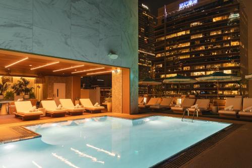 a pool in a hotel with chairs and a building at The Delphi Downtown LA in Los Angeles