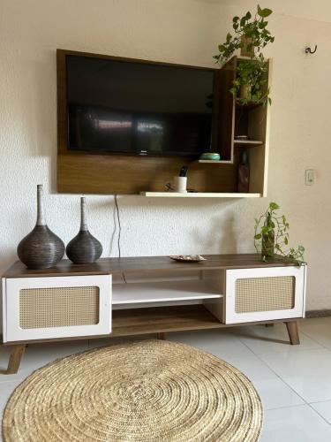 ein Wohnzimmer mit einem Fernseher an der Wand in der Unterkunft Casa da Cabana Guajiru in Trairi