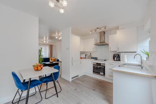a kitchen with white cabinets and a table and chairs at Lovely 2 Bedroom House in Cheshunt
