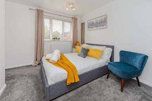 a bedroom with a bed and a blue chair at Lovely 2 Bedroom House in Cheshunt