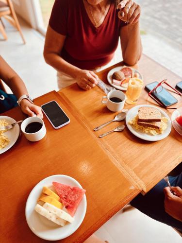 a woman sitting at a table with breakfast foods at Pousada Ilha Faceira in Florianópolis