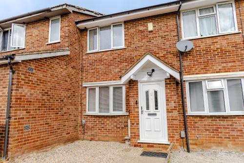 a brick building with a white door and windows at Lovely 2 Bedroom House in Cheshunt
