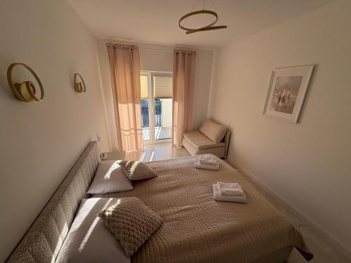 a bedroom with a large bed and a chair at Apartament BalticSea 11 Mielno in Mielno