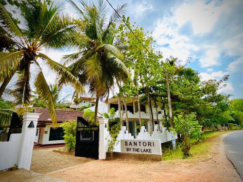 a sign in front of a house with a palm tree at Santori By The Lake in Anuradhapura