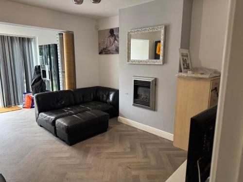 a living room with a black leather couch and a fireplace at Victoria Park in Bristol