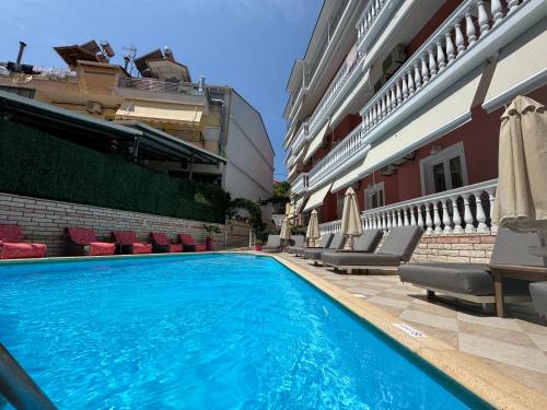 a swimming pool with chairs and umbrellas next to a building at Villa Antonis in Parga