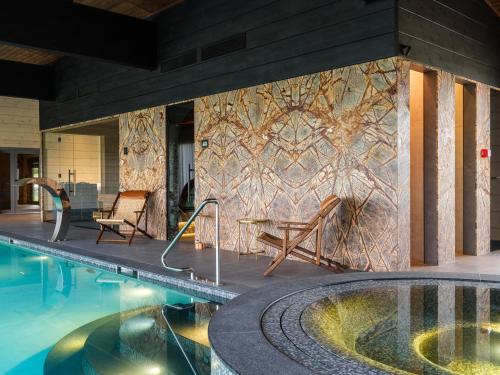 a swimming pool with a stone wall with a wall at SEOVILLAGE Resort & Spa in Ķeipene