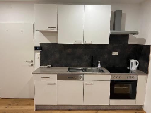 a kitchen with white cabinets and a sink at Main Square Loft Apartment for 6 in Wiener Neustadt