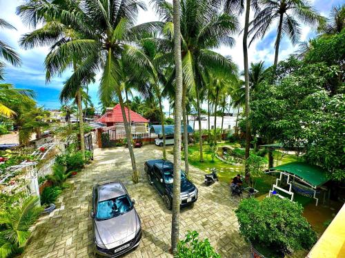 two cars parked in a parking lot with palm trees at Gem’s House in Mui Ne