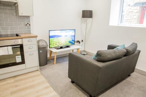 a living room with a couch and a flat screen tv at Cosy 1 Bedroom Apartment in Central Blackburn in Blackburn