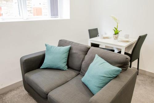 a couch with blue pillows in a living room at Cosy 1 Bedroom Apartment in Central Blackburn in Blackburn