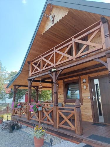 a large wooden cabin with a porch and a fence at Zielone Rykowisko - Myśliwski domek całoroczny in Blizów