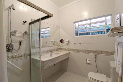a white bathroom with a sink and a shower at Pousada Villa Capivary Campos do Jordão in Campos do Jordão