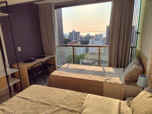 um quarto de hotel com duas camas e uma grande janela em Apto próximo à praia da Barra, com vista para o mar! em Salvador