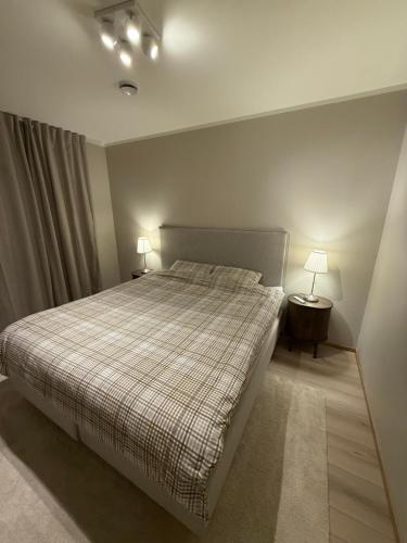 a bedroom with a bed with a plaid blanket and two lamps at Modern house at Senja in Silsand