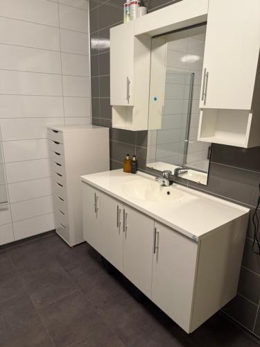 a white bathroom with a sink and a mirror at Modern house at Senja in Silsand