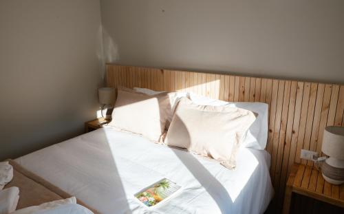 a bed with white sheets and pillows in a room at Refugio Andino Los Queñes in El Cerrillo