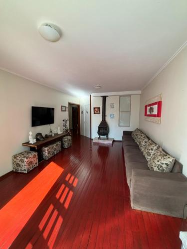 a living room with a couch and a flat screen tv at Casa do Rogerio Hostel - Unidade Shopping in Caxias do Sul