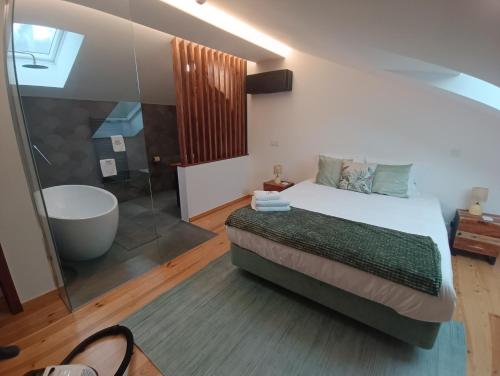 a bedroom with a large bed and a bath tub at Fragas do Cabril Eco & Wellness Lodge in Lousã