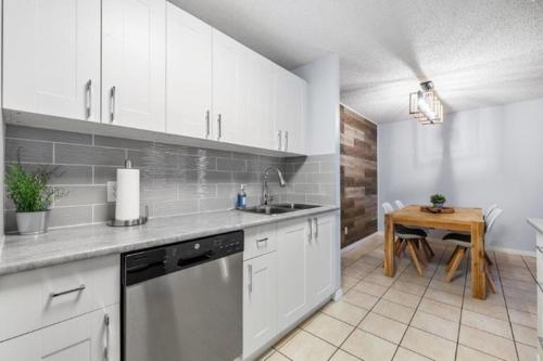 a kitchen with white cabinets and a sink and a table at Cozy & Spacious 2BR in Downtown very close to Stampede and 17th Ave with Parking and AC in Calgary