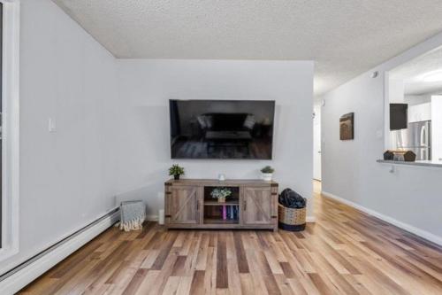 a living room with a tv and a wooden floor at Cozy & Spacious 2BR in Downtown very close to Stampede and 17th Ave with Parking and AC in Calgary