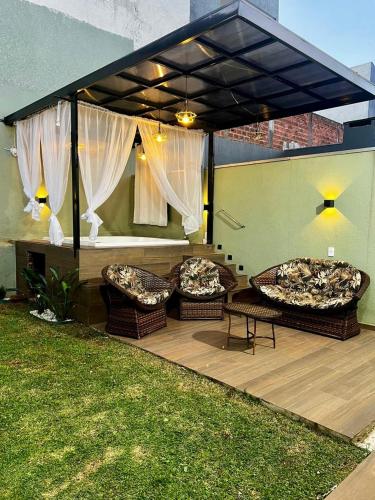 a covered patio with two chairs and a table at Casa Aconchegante Saboto in Foz do Iguaçu