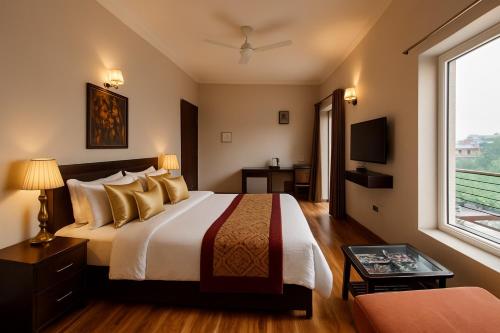 a hotel room with a bed and a window at Pearl Grand Boutique Cottage in Omaxe Anandam Vrindavan - #premium AC rooms with balcony #big parking #lift #garden #peaceful area #near prem mandir #property of the year #most awarded in Vrindāvan