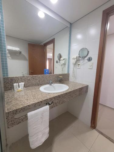 a bathroom with a sink and a mirror at Apt premium Próx Manauara shopping Bluetree Hotel in Manaus