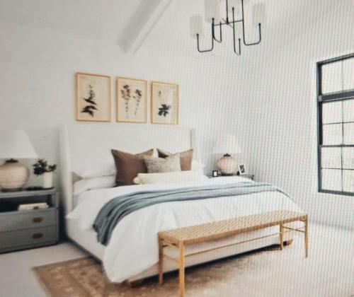 a white bedroom with a bed and a chandelier at Rural Villa Guesthouse in Naledi