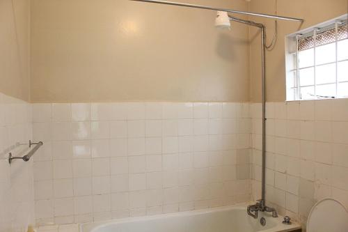 a bathroom with a tub and a toilet and a window at Charming 3-Bedroom Townhouse with Garden & Balcony - Lavington, Nairobi in Nairobi