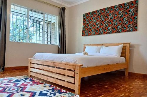 a bedroom with a bed and a picture on the wall at Charming 3-Bedroom Townhouse with Garden & Balcony - Lavington, Nairobi in Nairobi