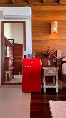 a red refrigerator in a room with a bedroom at Kamaiurá Pousada in Caraíva