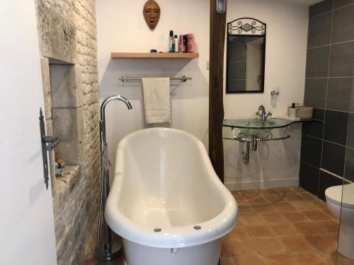 un bagno con vasca e lavandino di Bluebell cottage a Saleignes