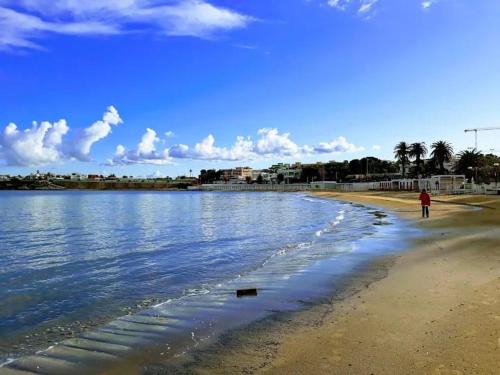 a person walking on a beach near the water at HOME SWEET HOME Casa vacanze e affitti brevi in Trani