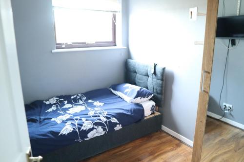 a bedroom with a bed with blue sheets and a window at Galleywood House in Great Baddow