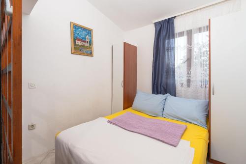 a small bedroom with a bed and a window at Apartments Vjeko in Nin