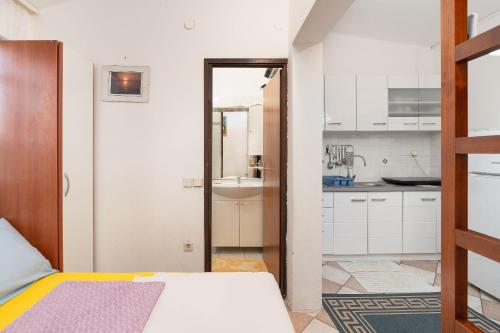 a bedroom with a bed and a sink and a kitchen at Apartments Vjeko in Nin