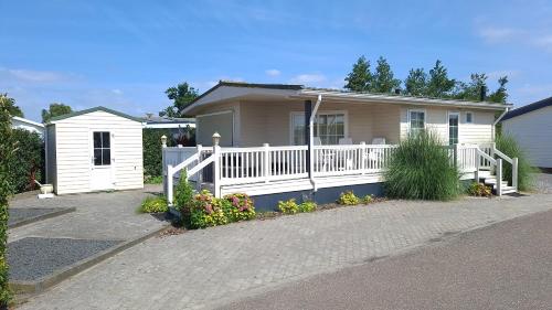 a house with a white fence and a porch at Chalet 128 Krabbenkreek in Sint Annaland